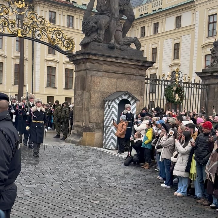 A changing of the guard ceremony with soldiers in uniform and a large crowd watching.