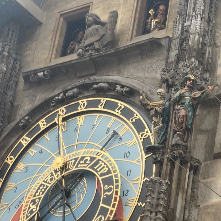Detailed view of Prague Astronomical Clock with skeleton, musician, and figures on stone facade.