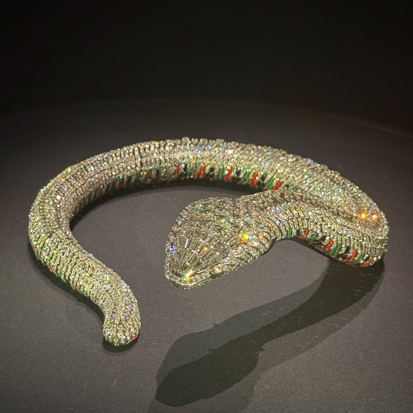 Diamond-encrusted snake bracelet with subtle red and green enamel details.