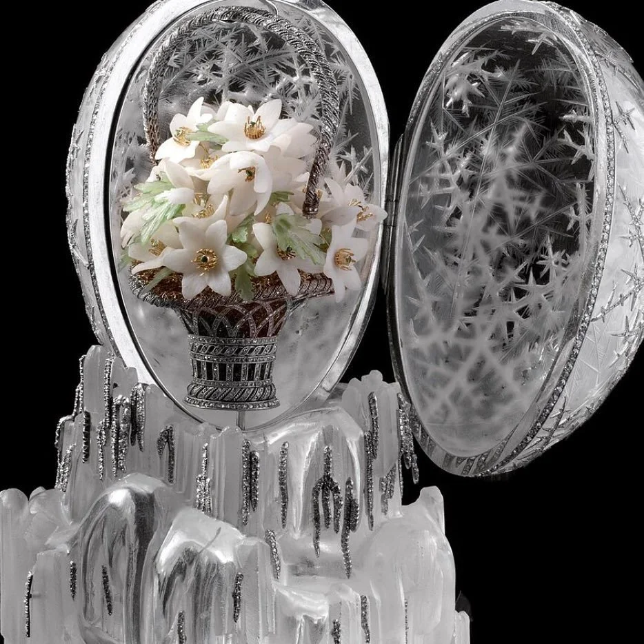 Open rock crystal egg with snowflake patterns, white flowers in basket, on icy base.